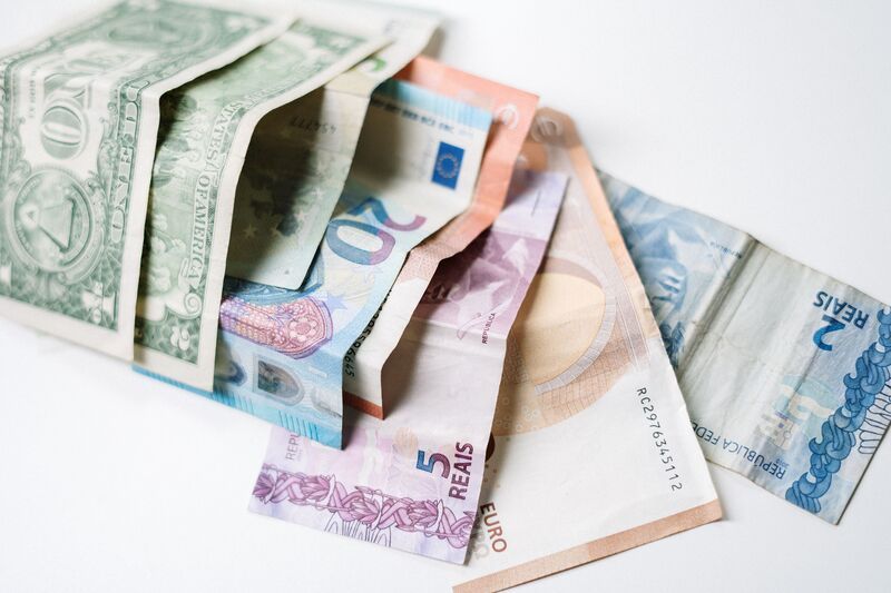Billets en dollars, euros et reais sur fond blanc
